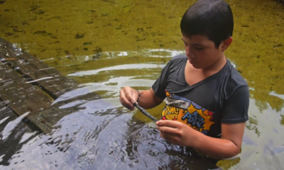 Un immagine del film: un ragazzo si bagna nelle acque del Rio Rojo e trova un pezzo di petrolio.